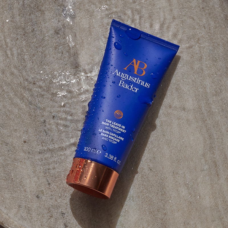 A model squeezes 'The Leave In Hair Treatment' by Augustinus Bader onto her hand in the shower